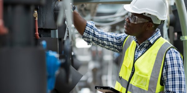 Male plumber engineer working at sewer pipes area at construction site. African American male engineer worker check or maintenance sewer pipe network system at construction sit